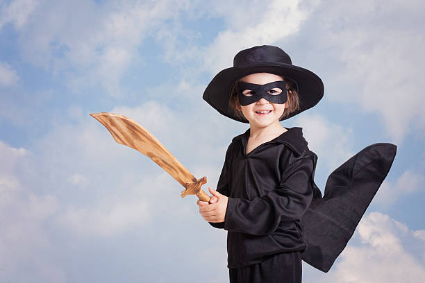 istock Superhero child with sward and costume on blue sky background 474858954