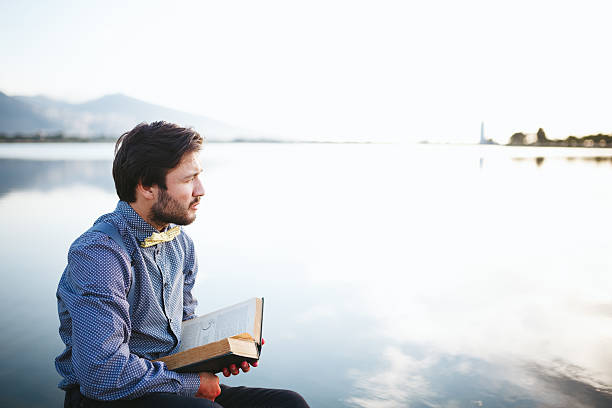 istock Young man reading book and looking away 474859136