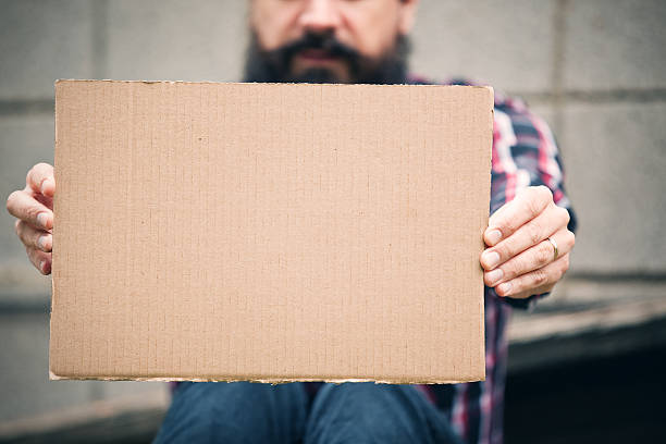 senzatetto uomo che tiene un vuoto segno di cartone - cardboard sign foto e immagini stock