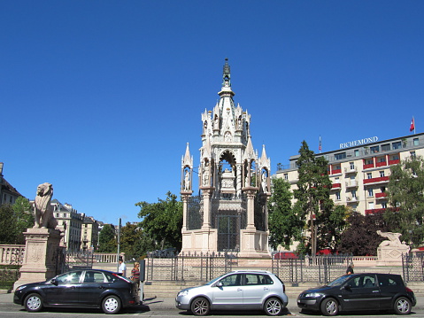 Geneva Brunswick monument in the Alps park nearby Geneva Lake under blue sky. Famous Brunswick Monument, one lion made of stone in the Alps park, Geneva in Switzerland. This monument contains the tomb of Charles II, Duke of Brunswick. The Duke left his fortune to the city of Geneva but asked it to build the replica of Verona.