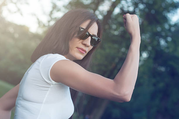 hermosa mujer flexionar los músculos - human muscle women bicep girl power fotografías e imágenes de stock