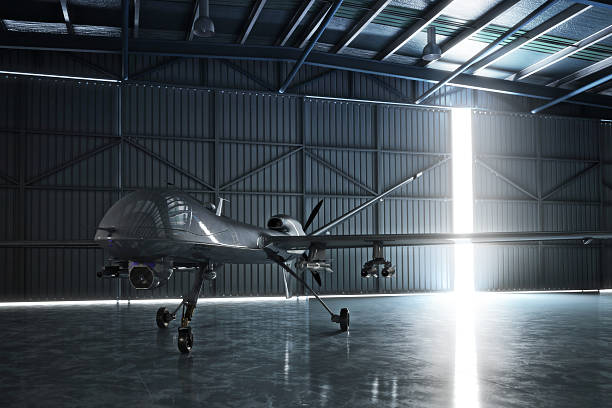 Awaiting flight. Lone drone U.A.V aircraft awaiting a military mission in a hanger. 3d model scene. airplane hangar stock pictures, royalty-free photos & images