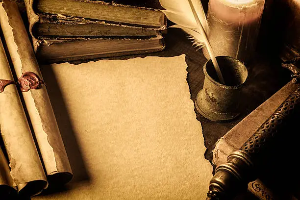 Blank parchment surrounded by books,scrolls and feather pen