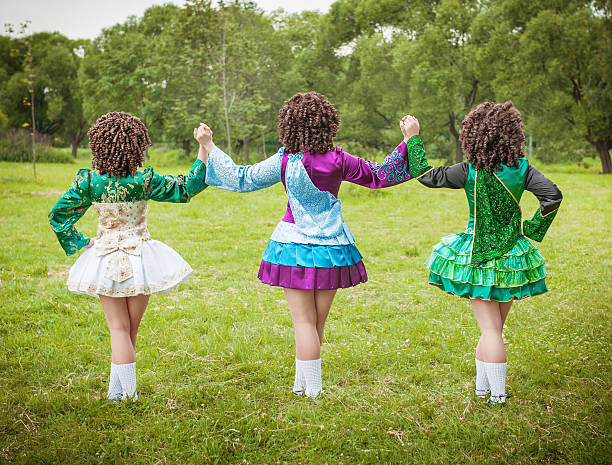 Three girls in irish dance dress and wig posing outdoor stock photo