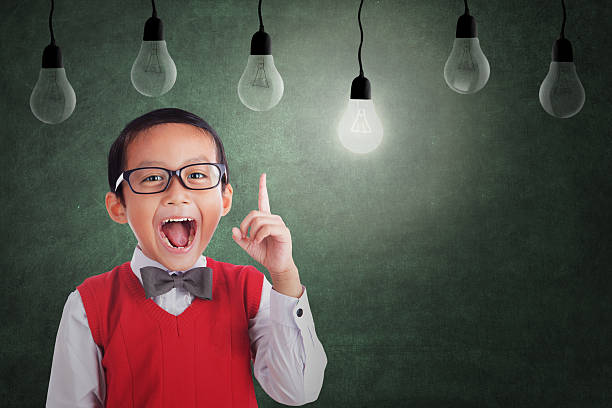 Asian boy has idea under light bulb in class Asian student boy has an idea under light bulbs in class nerd kid stock pictures, royalty-free photos & images