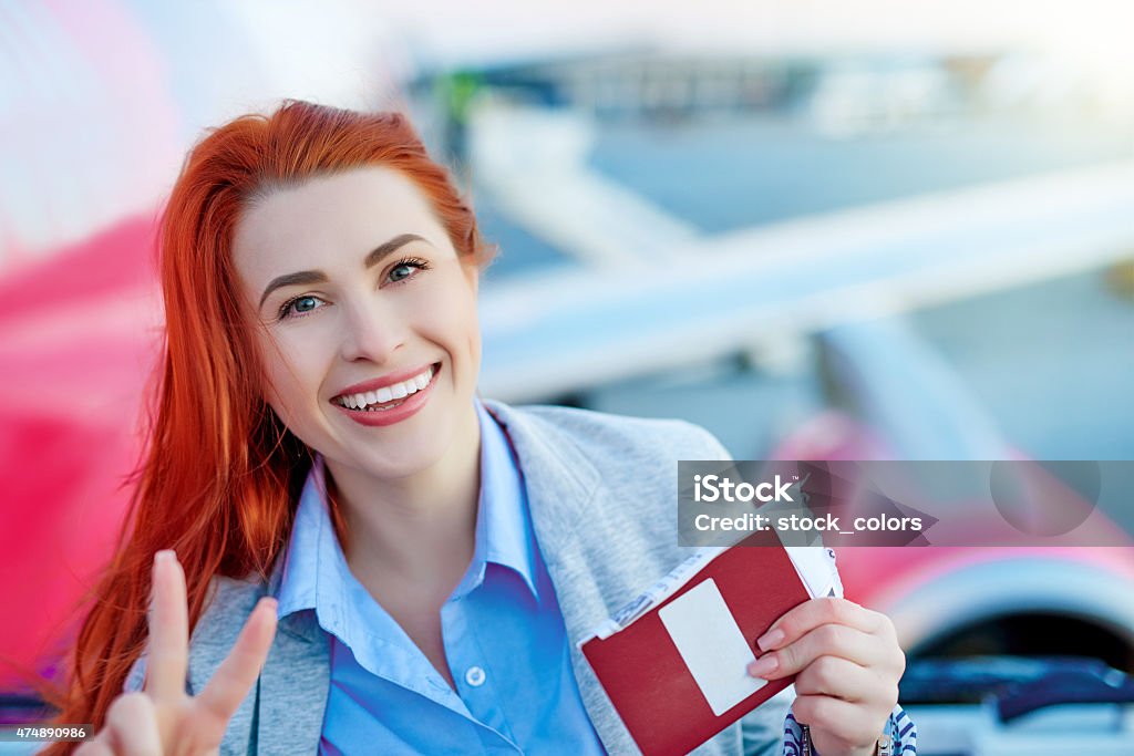 thumbs up for vacation happy red hair woman with airplane tickets showing thumbs up and smiling. Laughing Stock Photo
