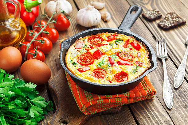 Frittata in cast iron skillet on a wood surface stock photo
