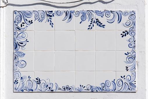 Antique blue and white antique Spanish or Portuguese tile panel on a white wall with copy space.