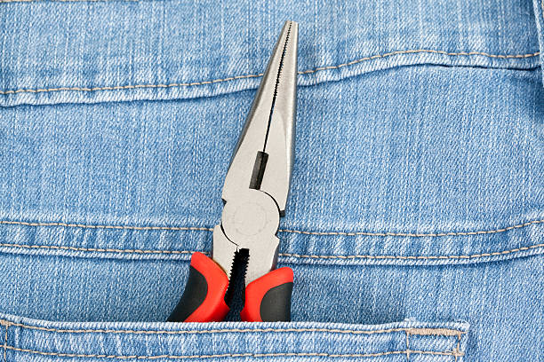 Pliers in the back pocket of denim jeans.