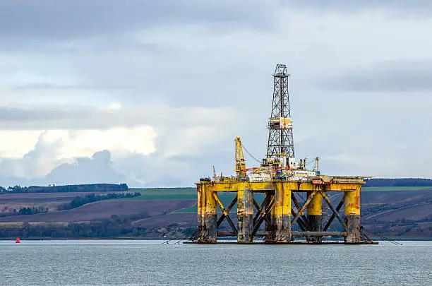 Old oil rig anchored in shallow waters off the coast of Scotland and cloudy sky