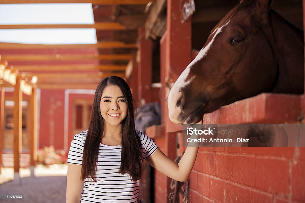 Cute Latin woman and her horse Portrait of a happy young woman smiling next to her horse at the stables 20-29 Years Stock Photo