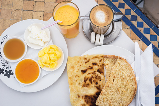 Coffee with milk, fresh orange juice and toast with crepes along with jam, honey, butter and cheese