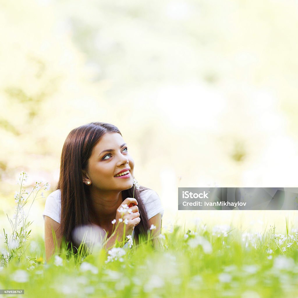 Woman laying in sunny spring park Young woman laying in sunny spring park with white flowers Adult Stock Photo