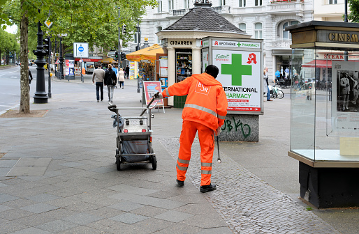 Berlin, Germany - May 17, 2015: a garbage man cleans a walkway on the Kurfürstendamm in Berlin