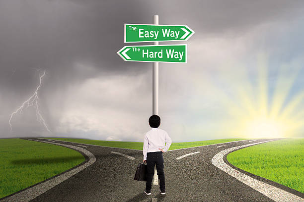 istock Little boy looking at sign of easy vs hard way 474932126