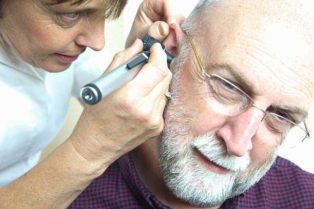 Nurse inspects patient's ear with an auroscope Nurse inspects patient's ear with an auroscope - the ear drum is evident from the image - all clear! ear drumm stock pictures, royalty-free photos & images