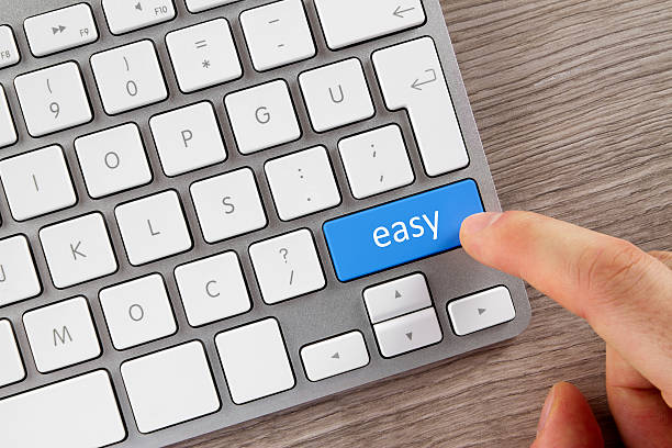 human finger is pushing easy button on computer keyboard - moeiteloos stockfoto's en -beelden