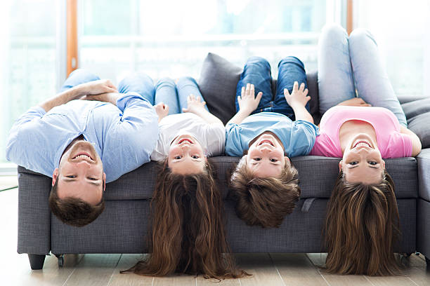 familie auf sofa liegen auf den kopf gestellt - women group of people lying down mother stock-fotos und bilder