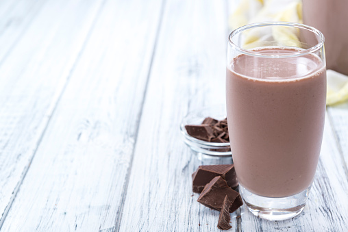 Cold Chocolate Milk drink (close-up shot) on wooden background