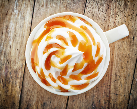 cup of a fresh caramel latte with whipped cream, top view