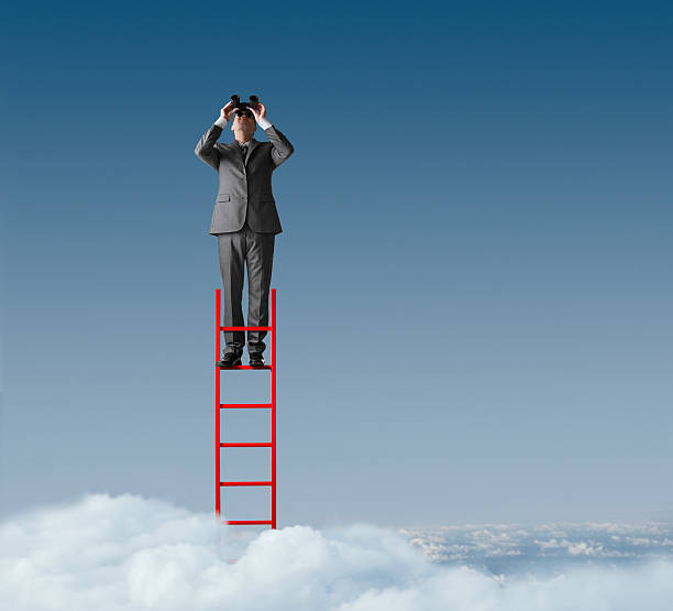 istock Businessman standing on ladder looking through binoculars 474954433