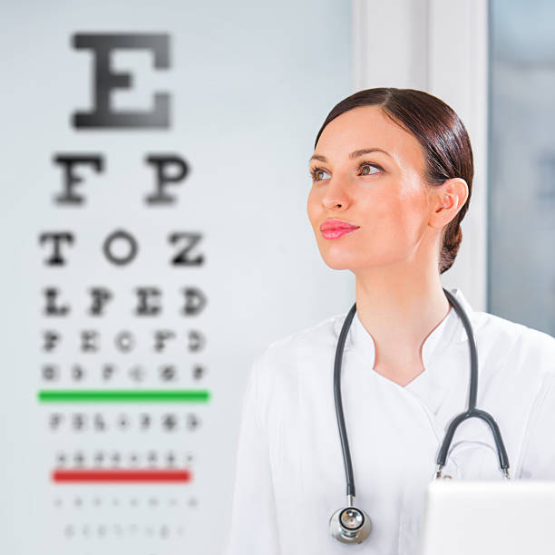 mujer de pie en la recepción óptico de oftalmología prueba en el hospital - doctor reading chart human eye fotografías e imágenes de stock