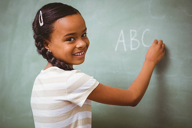 istock Cute little girl writing ABC on blackboard 474959686
