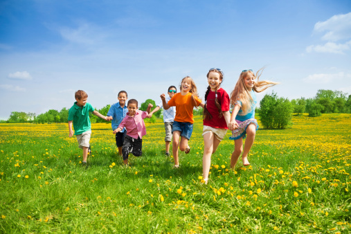 Large group of kids running in the dandelion spring field