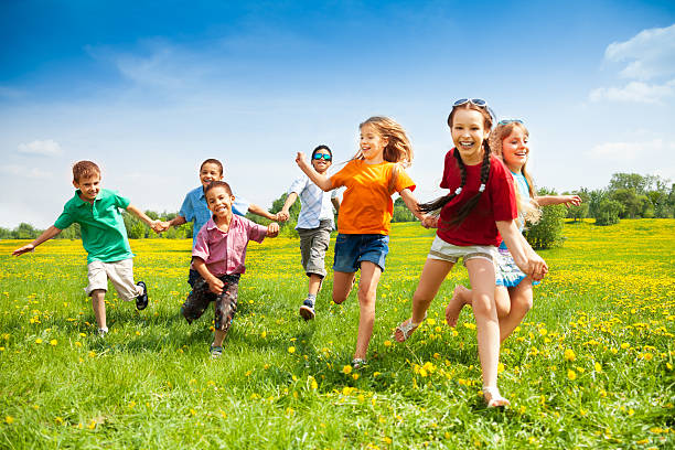 gruppo di bambini felici in esecuzione - spring child field running foto e immagini stock