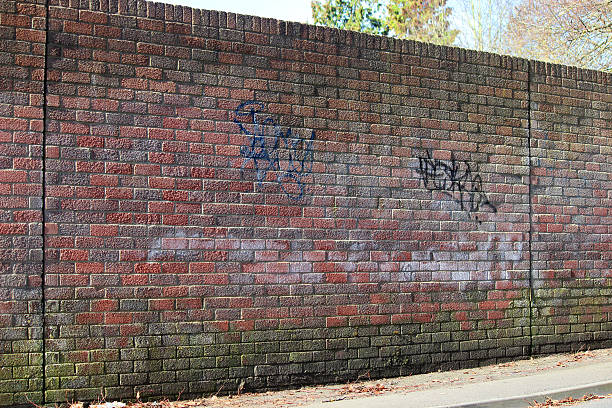 istock Image of dirty red-brick wall with graffiti tags spray painted 474962302