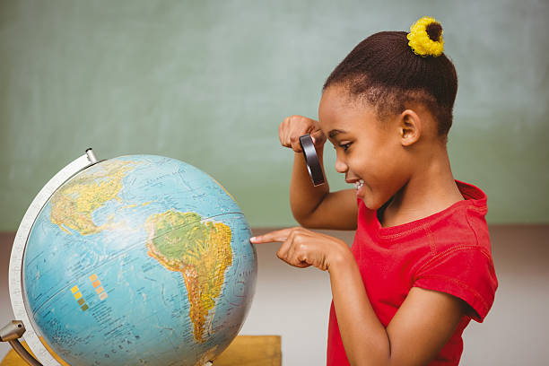 istock Little girl looking at globe through magnifying glass 474964032