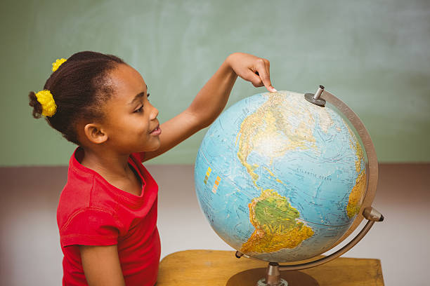 istock Little girl pointing at globe in classroom 474964036
