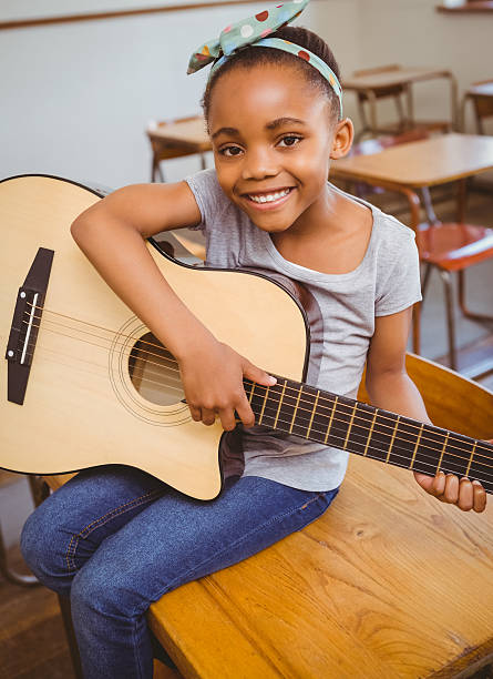 istock Little girl playing guitar in classroom 474964322