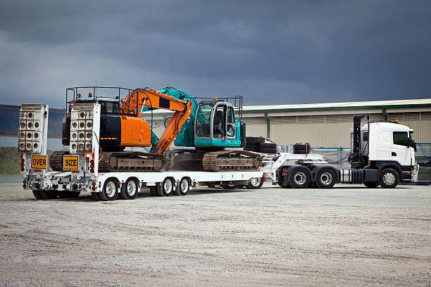 Truck Towing Float Trailer and Hydraulic Excavators stock photo
