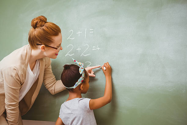 lehrer, die unterstützung von mädchen schreiben auf tafel im klassenzimmer - blackboard writing chalk teacher stock-fotos und bilder