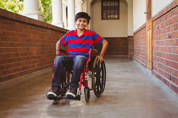 Boy sitting in wheelchair at school corridor Portrait of cute little boy sitting in wheelchair in school corridor wheelchair photos stock pictures, royalty-free photos & images