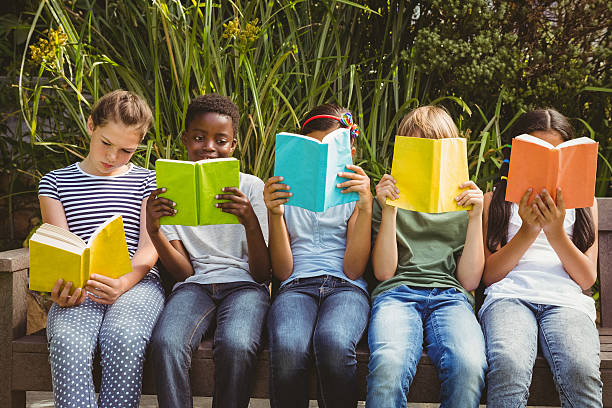 istock Children reading books at park 474967024