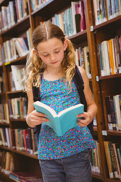 istock Girl reading book in library 474967060
