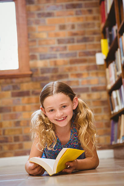 istock Cute little girl reading book in library 474967092