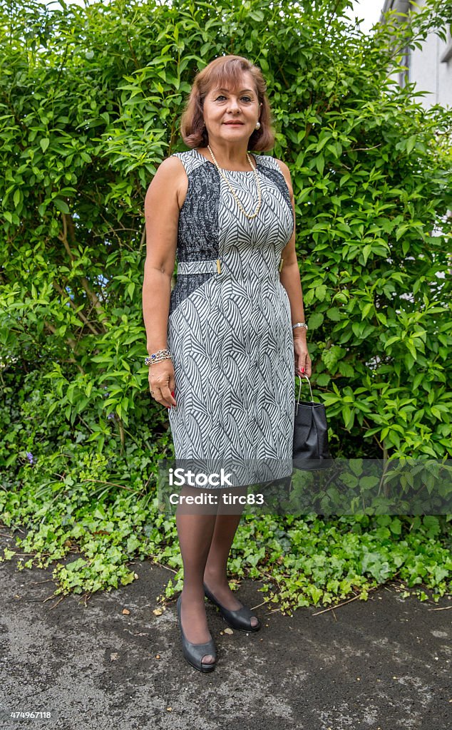 Mature hispanic woman portrait against green foliage 2015 Stock Photo