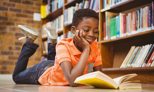 Niño atractivo leyendo libro en la biblioteca photo