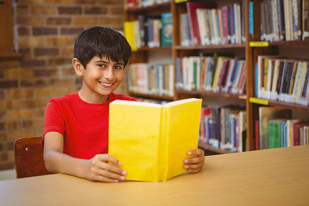 istock Portrait of boy reading book in library 474969378