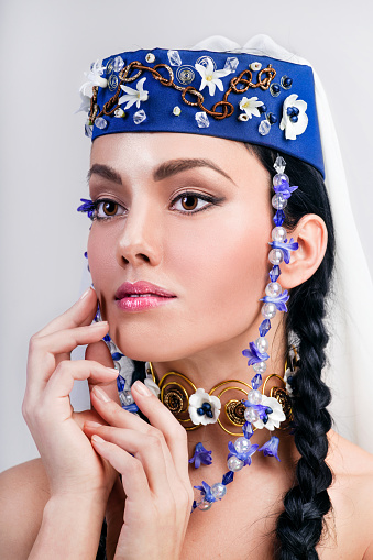 Close-up portrait of beautiful Georgian woman wearing national accessories decorated with flowers.