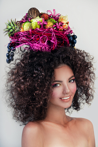 Close-up portrait of beautiful Cuban woman wearing hat decorated with fruits.
