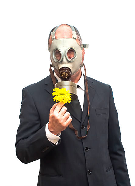 istock Businessman with gas mask looking at an flower 474976902