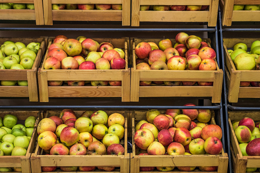 Organic apples in wooden boxes in the supermarket are sorted by varieties