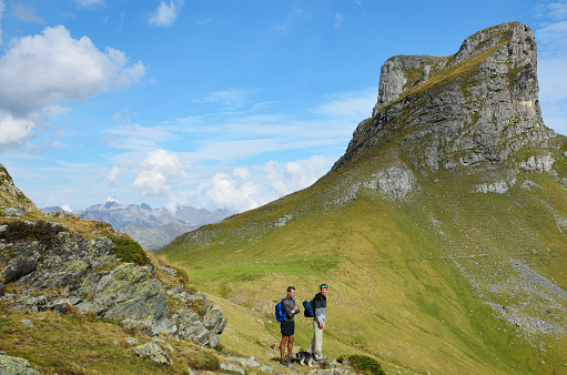 The tourists are standing on the green slope of the mountain Pic Casterau in the Atlantic Pyrenees.