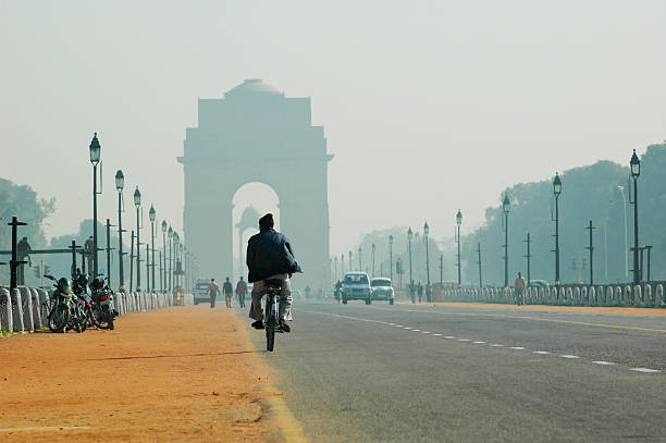Rajpath boulevard and India Gate in New Delhi, India. New Delhi, India - December 6, 2005: Bicycle rider riding toward India Gate along the Rajpath boulevard in New Delhi, India.  delhi stock pictures, royalty-free photos & images