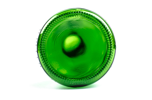 A selective focus shot of green glass bottles in rows on a black background