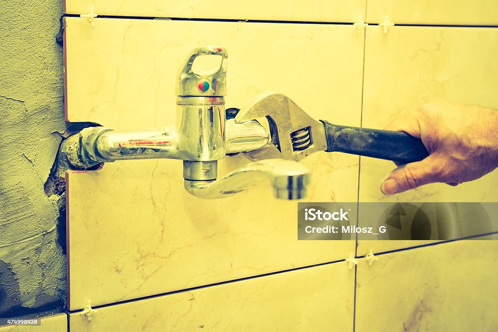 Vintage photo of plumbers hands tightening a water pipe. Vintage photo of plumbers hands tightening a water pipe. Authentic and accurate content depiction. 2015 Stock Photo